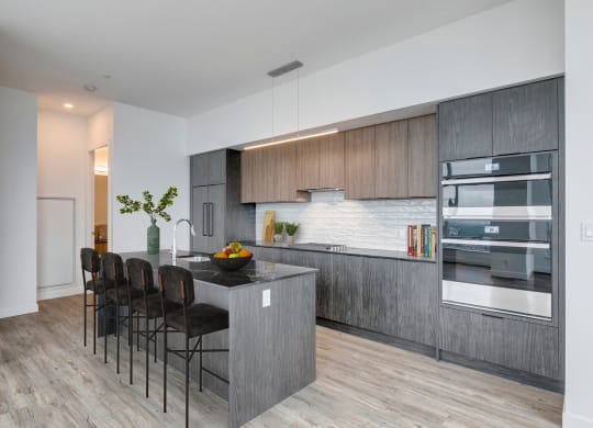 a modern kitchen with a large island with a counter top and chairs at BLVD Beltline, Calgary, AB