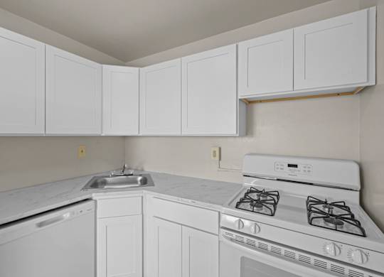 A white kitchen with a stove, sink, and cabinets at Kensington House, Kensington, Maryland