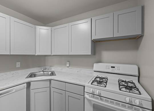 A kitchen with white cabinets and a white stove top oven at Kensington House, Kensington