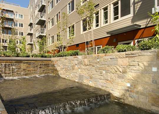A small waterfall in a courtyard surrounded by buildings.
