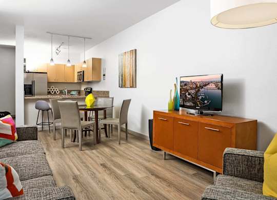 A living room with a grey couch, a yellow pillow, a wooden cabinet, and a painting on the wall.