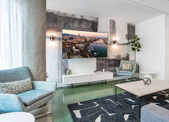 A living room with a couch, a chair, a coffee table, and a large painting on the wall.