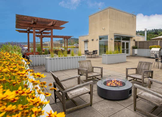 A patio with a fire pit and chairs.