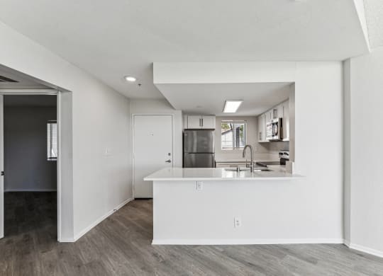 an open kitchen and living room with white walls and wood flooring
