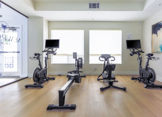 a row of exercise bikes in a room with a yoga studio
