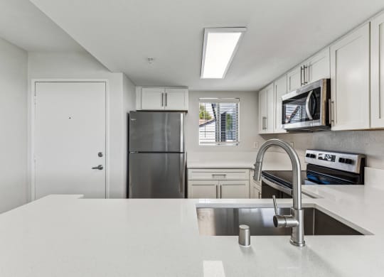 a white kitchen with stainless steel appliances and a white counter top