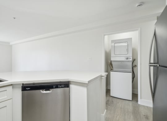 a white kitchen with stainless steel appliances and a white counter top