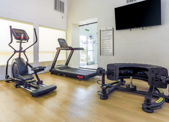 a gym with exercise equipment and a tv on the wall