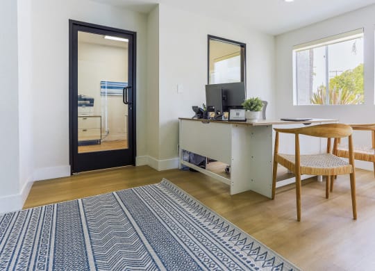 a living room with a desk and a door to a kitchen