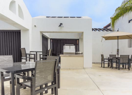 a patio with tables and chairs and an umbrella