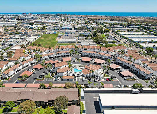 A bird's eye view of a residential area with apartment buildings and a pool.