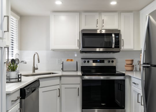 a kitchen with white cabinets and black appliances