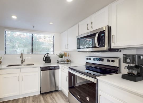 a kitchen with white cabinets and stainless steel appliances