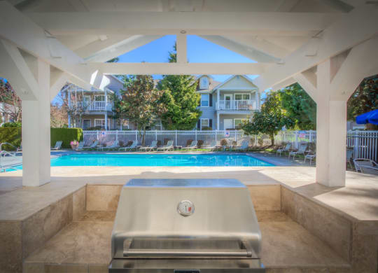 a swimming pool with a hot tub and a pool house in the background