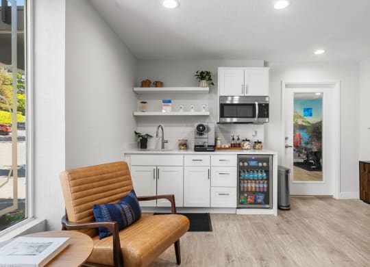 a living room with a chair and a kitchen with a microwave