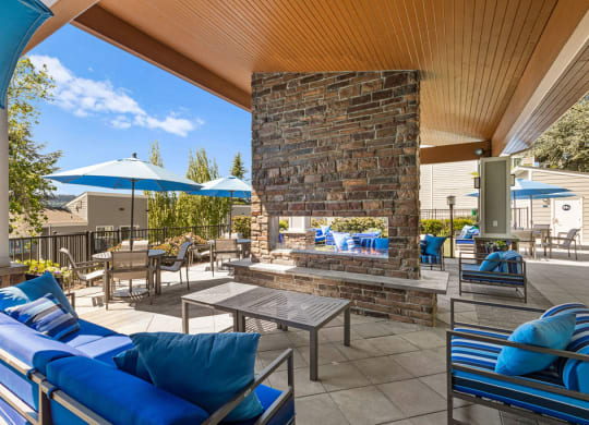 the outdoor patio has a fireplace and tables with umbrellas