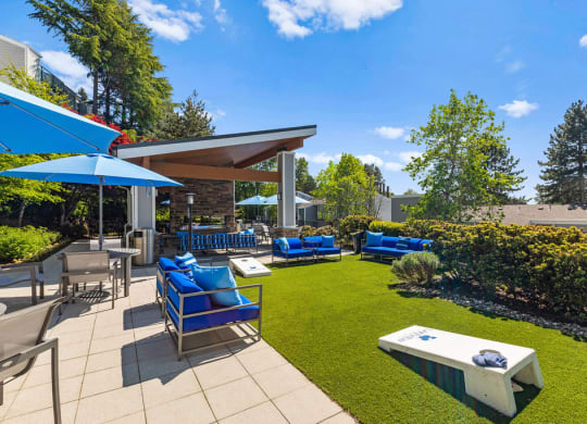 a patio with blue chairs and umbrellas and a lawn