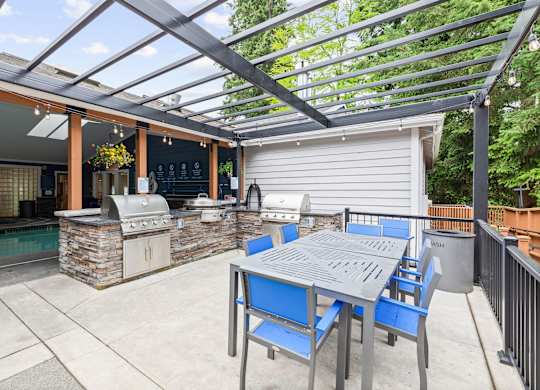 A patio with a table and chairs and a grill.