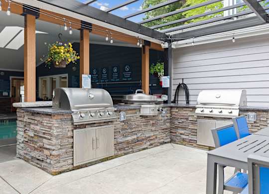 A patio with a stone barbecue and a table.