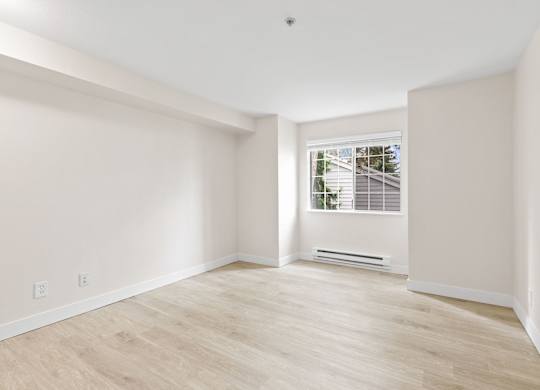 A room with a window and a wooden floor.