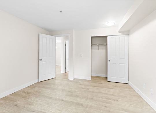 A room with white walls and wooden flooring with two white doors.