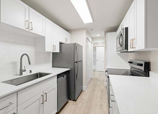 A modern kitchen with white cabinets and a black fridge.