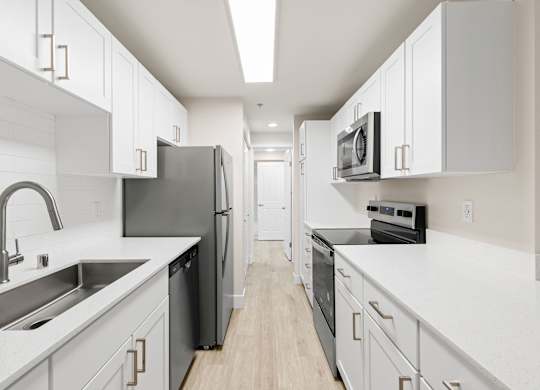 A modern kitchen with white cabinets and black appliances.