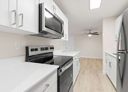 A kitchen with white cabinets and black appliances.