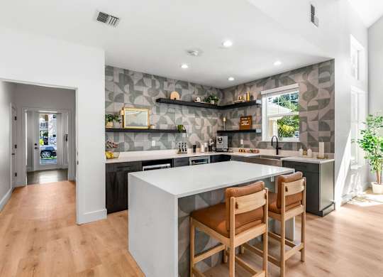 A kitchen with a white island and wooden chairs.
