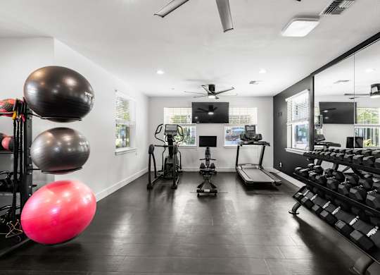A gym with a variety of equipment including a treadmill, a rowing machine, and a stationary bike.