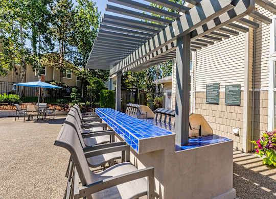 A patio with a blue table and chairs under a striped awning.
