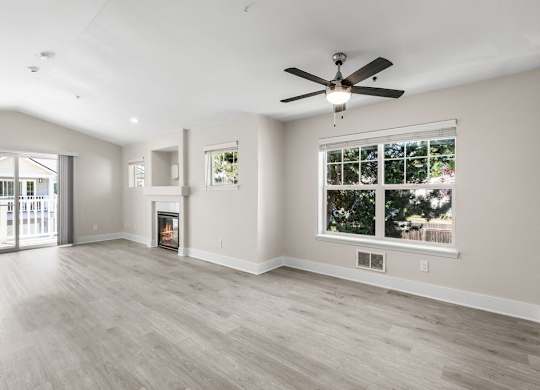 A spacious living room with a fireplace and a ceiling fan.