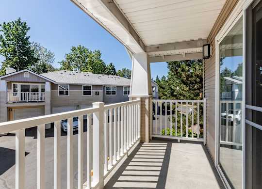 A white balcony with a glass door and a white railing.