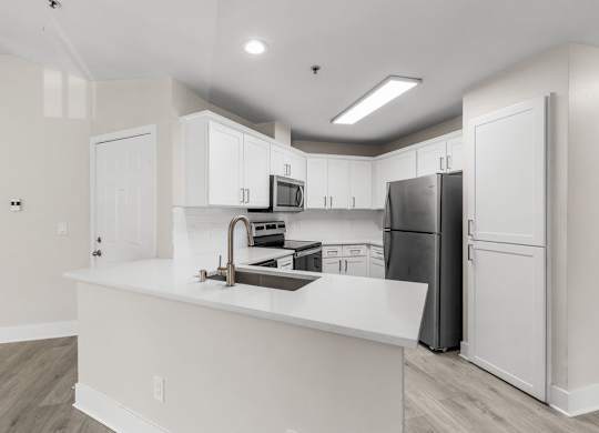 A kitchen with white cabinets and a black refrigerator.