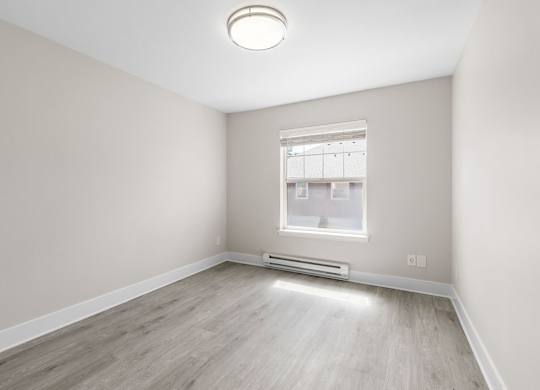 A room with a window and a radiator on the wall.