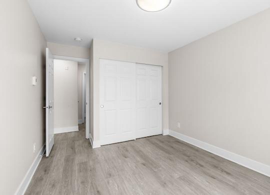 A white door is in the middle of a room with wood flooring.