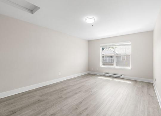 A room with a window and a wooden floor.