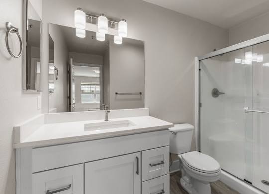 A white bathroom with a sink, toilet, and mirror.