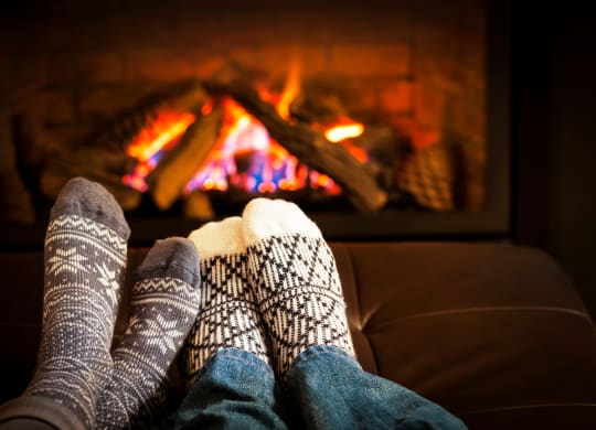 a person with feet up on a couch in front of a fireplace