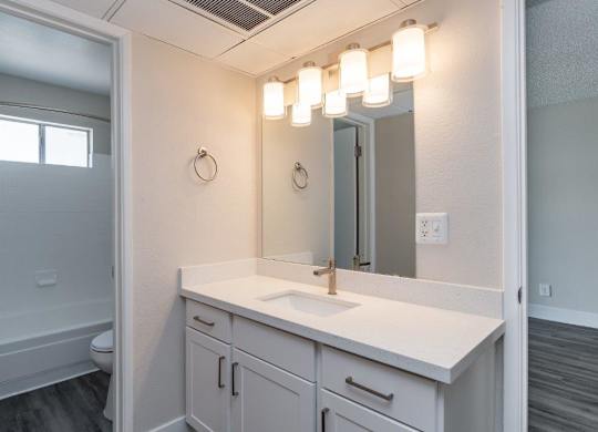 A bathroom with a white sink and a mirror above it.