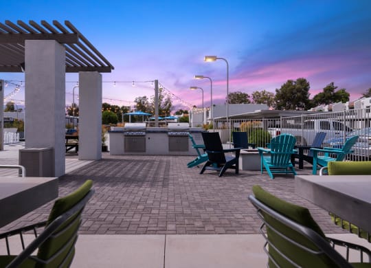 a patio with chairs and a grill at dusk