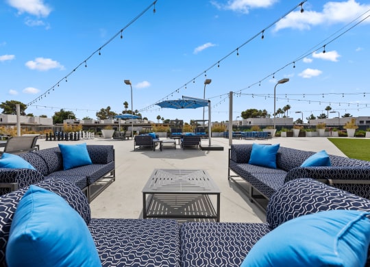 a seating area with blue couches and a table with blue pillows and a blue umbrella