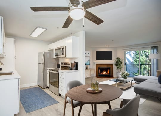 a kitchen and living room with a ceiling fan and a fire in the fireplace