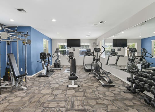 a gym with weights and cardio equipment in a building with blue walls