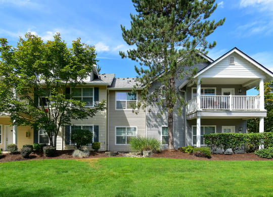 the view of an apartment building with a lawn and trees