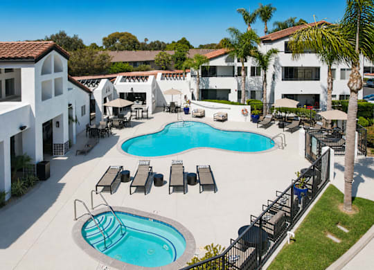 A large swimming pool surrounded by lounge chairs and umbrellas.