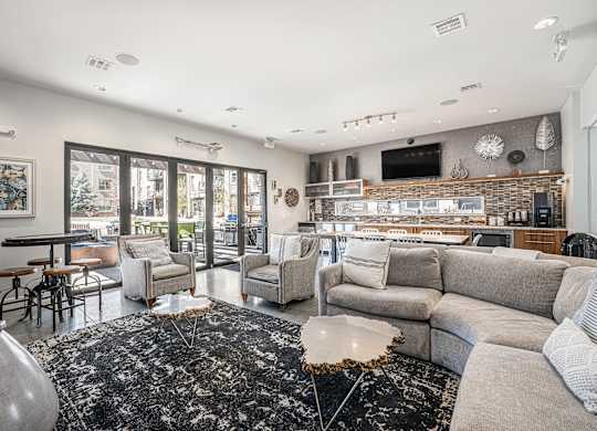 A modern living room with a black and white rug, a grey sofa, and a flat screen TV mounted on the wall.