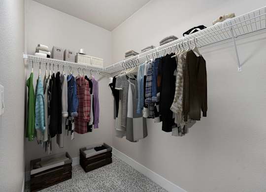 A white closet with clothes hanging on a rail.