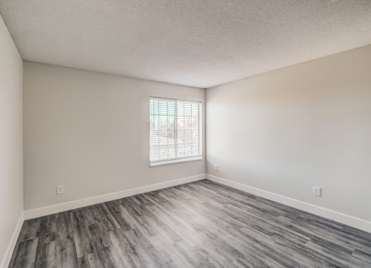an empty bedroom with hardwood floors and a window