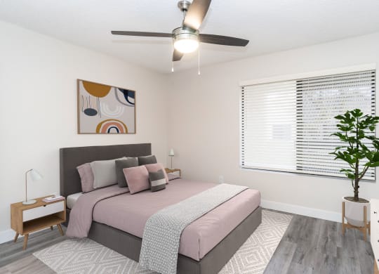 a bedroom with a large window and a ceiling fan